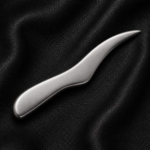Stainless steel faux knife with a blunt non-cutting edge displayed on a black leather background.