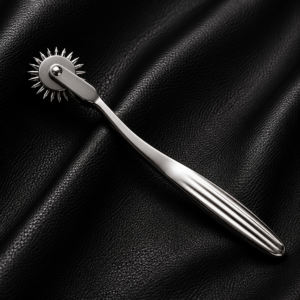 Stainless steel Wartenberg wheel with a precision rotating pinwheel on a black leather background.